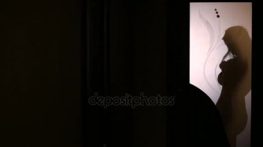 Bir cam kapının arkasında kıyafet değiştirerek bir kadın silueti. O iç çamaşırı alır