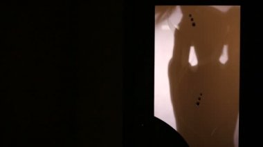 Bir cam kapının arkasında bir kadın silueti. Kuyruk saçını toplar