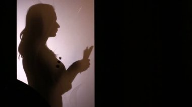 Bir cam kapının arkasında bir paket kağıt para sayma bir kadın silüeti.