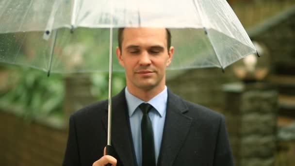 Frustrado pelo tempo, de pé sob o guarda-chuva durante a chuva. Homem infeliz de terno — Vídeo de Stock