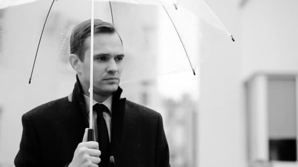 Gefrustreerd door het weer, permanent onder de paraplu tijdens de regen. Ongelukkig man in een pak — Stockvideo