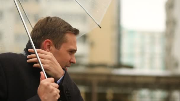 Frustrado por el clima, de pie bajo el paraguas durante la lluvia. Hombre infeliz en un traje — Vídeos de Stock