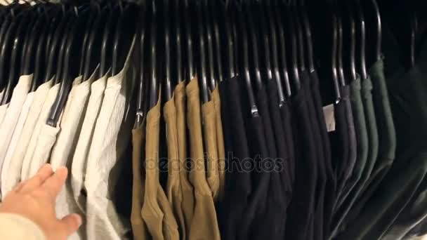 Mann kauft im Bekleidungsgeschäft ein, wählt Kleidung — Stockvideo