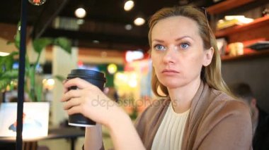 Bir kadın bir fast food café'de kahve içiyor. Tek kullanımlık Kupası. kahve