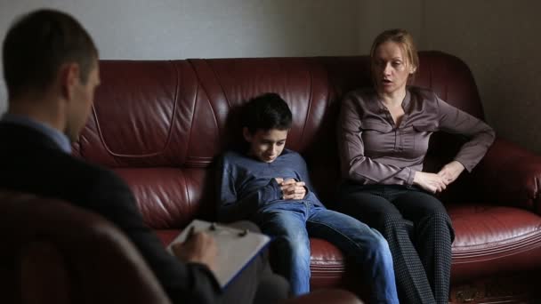 Raadpleging van een psycholoog. Mannelijke psycholoog overlegt met een vrouw en haar tiener zoon, familie counseling — Stockvideo