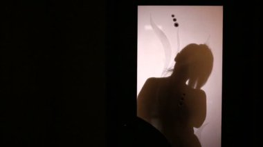 Bir cam kapının arkasında kıyafet değiştirerek bir kadın silueti. O iç çamaşırı alır