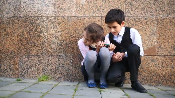 Triste ragazzo e ragazza studenti seduti per strada e guardando il tuo telefono , — Video Stock