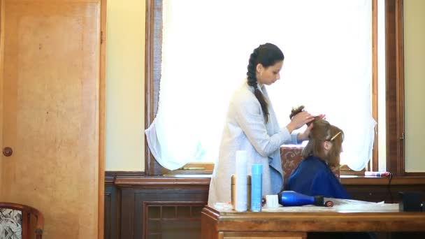 A hairdresser puts her hair through a hair dryer with a girl with short hair — Stock Video