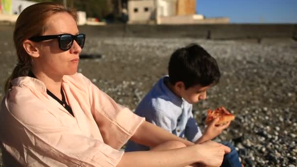 Crianças com mãe comendo pizza na praia — Vídeo de Stock