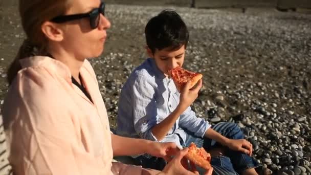 Дети с матерью едят пиццу на пляже — стоковое видео