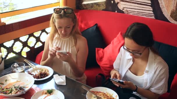 Друзья едят китайскую еду в китайском ресторане. Девушки с телефонами в ресторане — стоковое видео