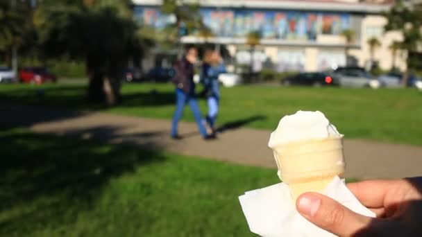 Een man is het eten van fast-food ijs tegen de achtergrond van een wazig stad straat. — Stockvideo