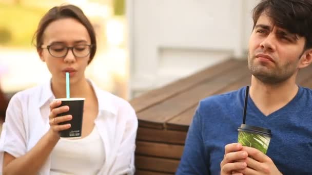 Un par de chicos y una chica están tomando café y charlando en un café informal al aire libre. Comida rápida — Vídeos de Stock
