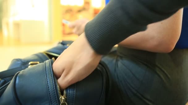 Женщина, сидящая на скамейке в торговом центре, не подозревает, что ее бумажник был украден хитрым карманником . — стоковое видео