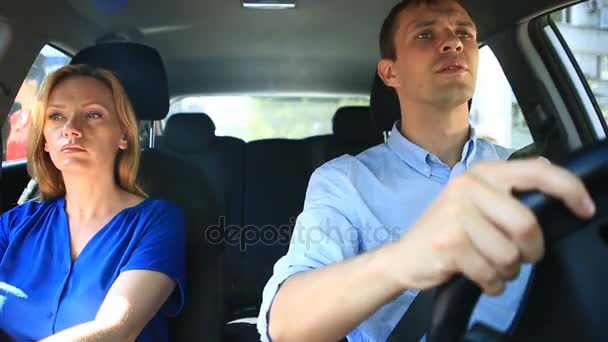 Casal dirigindo no carro, um homem e uma mulher andam juntos no carro pelas ruas da cidade e olham em volta — Vídeo de Stock