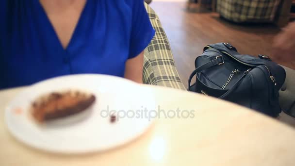 Una donna in un bar non sospetta che il suo portafoglio sia stato rubato da un furbo borseggiatore. Lei beve caffè con una torta, il ladro ruba un portafoglio da una borsa — Video Stock