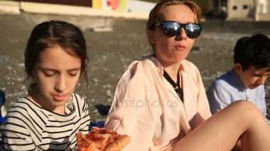 Çocuk annesiyle kumsalda pizza yemek
