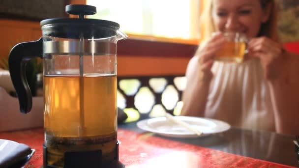 Женщина пьет зеленый чай из прозрачного чайника. Друзья едят китайскую еду в китайском ресторане — стоковое видео