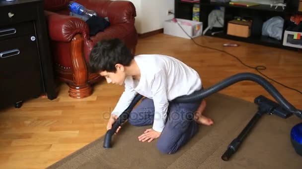 Le garçon nettoie le tapis dans la chambre avec un aspirateur — Video