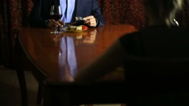 Romantik bir çift takım elbiseli bir adam ve bir kadın bir ızgarada pişmiş kemik içine pirzola bir parça keser. Seksi adam yeme et ve şarap