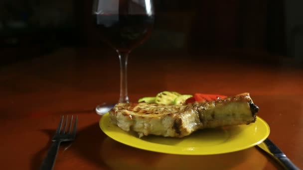 Gros plan des escalopes sur les os cuites sur un gril. La viande grillée se trouve sur un plateau avec des légumes grillés. A proximité se trouve un verre de vin rouge — Video