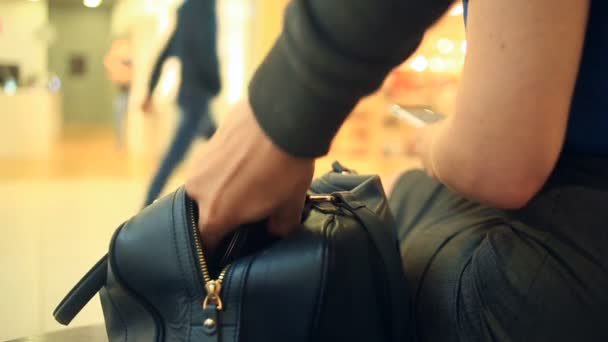 Eine Frau, die in einem Einkaufszentrum auf einer Bank sitzt, ahnt nicht, dass ihr Portemonnaie von einem listigen Taschendieb gestohlen wurde. — Stockvideo