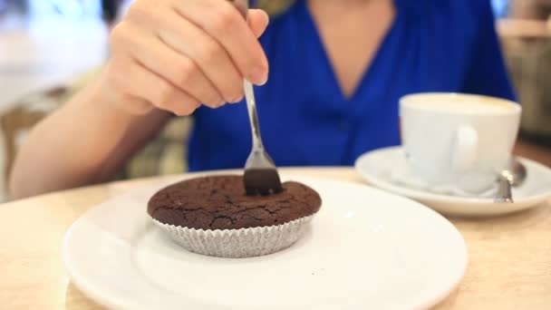 Γυναίκα σε ένα καφέ που πίνει καφέ με κέικ σοκολάτας — Αρχείο Βίντεο