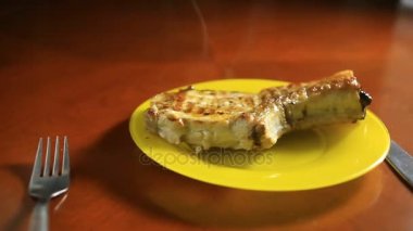 Bir kemik üzerinde bir pirzola close-up bir ızgarada pişirilir. Izgara et ızgara sebze ile bir tepside yatıyor. Sıcak, Buhar