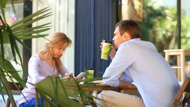 Coppia innamorata in un caffè all'aperto. Uomo e bellissima donna ad un appuntamento. Tutti guardano il suo cellulare. — Video Stock