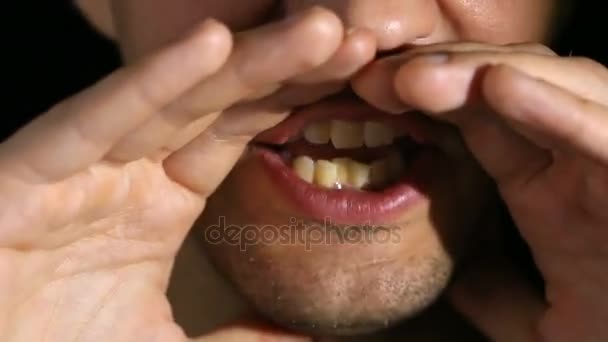 De kreten van de man in de camera op een zwarte achtergrond. Mond en grijns close-up — Stockvideo