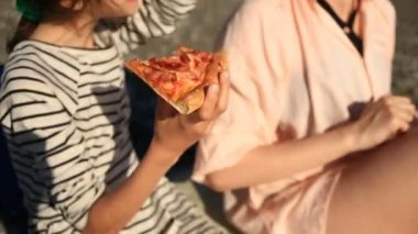 Çocuk annesiyle kumsalda pizza yemek