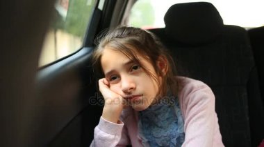 Arabada sıkılan küçük kız pencereden dışarı bakıyor. Sokak yansıması.