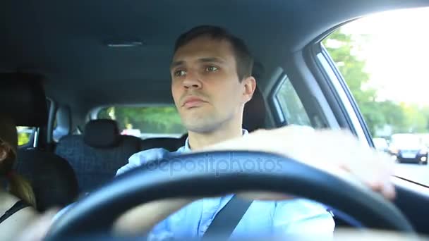 En man kör en bil, en man enheter i bilen genom gatorna i staden och glatt chattare med passageraren, skrattar. Killen bakom ratten — Stockvideo