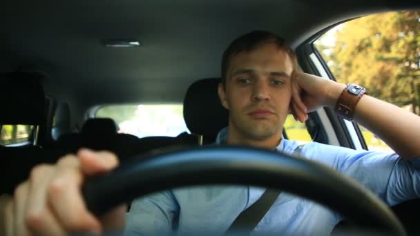 Seorang pria mengendarai mobil, seorang pria berkendara di dalam mobil melalui jalan-jalan kota dan riang obrolan dengan penumpang, tertawa. Guy di belakang kemudi — Stok Video