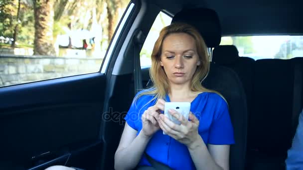 Дівчина їде в машині поруч з водієм і розмовляє по телефону — стокове відео