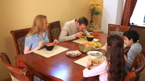 La familia cena en casa en el comedor. Niños adolescentes, gemelos y sus padres — Vídeo de stock