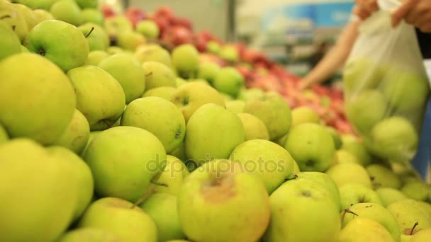 野菜の棚の上のスーパー マーケットの女性は、野菜や果物を買います。男がリンゴを選択します。 — ストック動画