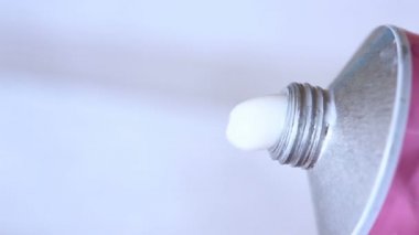 Beyaz zemin üzerinde bir tüp dışarı sıkılmış beyaz krem nemlendirici