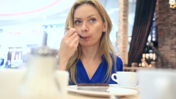 Woman in a cafe drinking coffee with chocolate cake — Stock Video