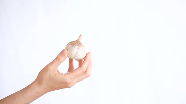 Mano femminile che tiene l'aglio su sfondo bianco — Video Stock