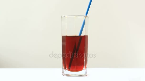 Someone drinks the juice through a pipe for drinking. Close-up isolated on white background. — Stock Video