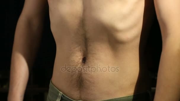 Naken torsoen av en ung mager man på en svart bakgrund. — Stockvideo