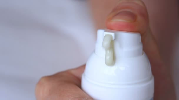 Crema blanca hidratante exprimida de un tubo sobre un fondo blanco — Vídeos de Stock
