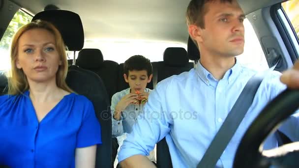 Семья, мама, папа и сын едут в машине, сын ест гамбургер — стоковое видео