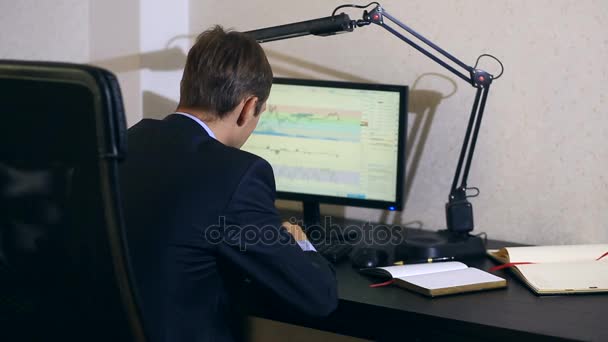 Бізнесмен спостерігає за змінами в розкладі валютного обміну, дивлячись на монітор комп'ютера — стокове відео