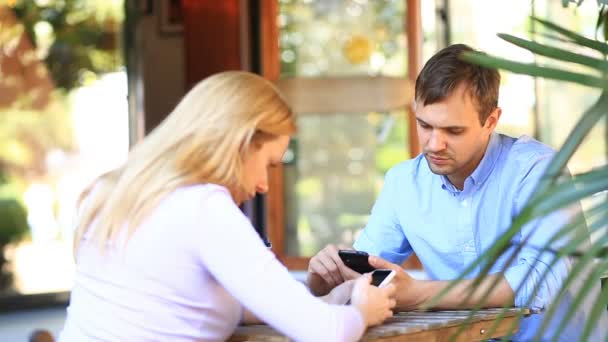 Coppia innamorata in un caffè all'aperto. Uomo e bellissima donna ad un appuntamento. Tutti guardano il suo cellulare. — Video Stock