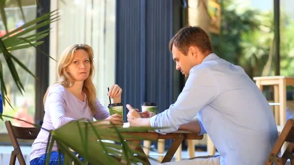 屋外カフェで愛のカップル。男とデートで美しい女性。誰もが彼の携帯電話を見てください。 — ストック動画