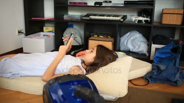 Ένα μικρό κορίτσι αποποιείται την εργασία της, παίζει στο κινητό. Καθαρισμός στο παιδικό δωμάτιο. Διαταραχή στο έφηβος δωμάτιο — Αρχείο Βίντεο