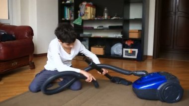 Çocuk bir elektrikli süpürge ile odada halı temizler