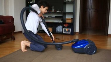 Çocuk bir elektrikli süpürge ile odada halı temizler